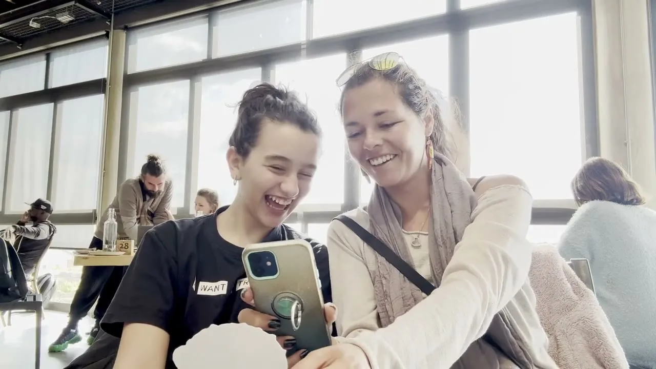 Two women laughing at a sticker animation on a phone