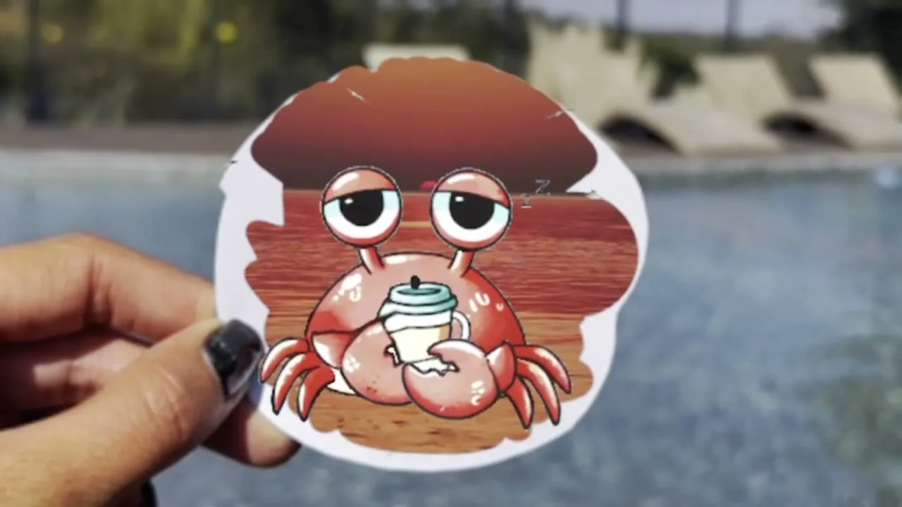 A hand holding a Seven Seas crab sticker beside a pool