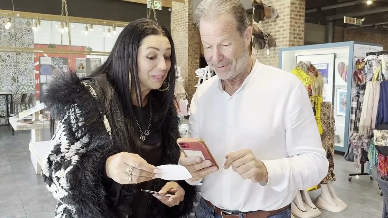 A couple in a shop looking at an animated sticker on a phone